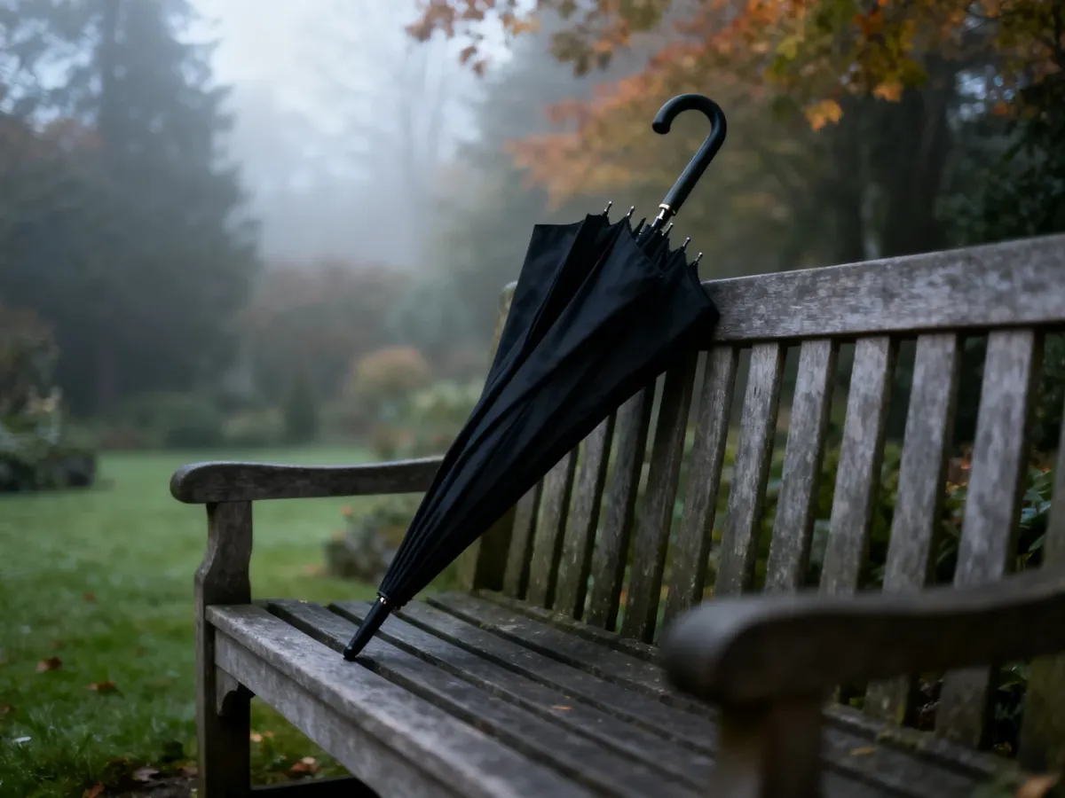 Czarny parasol na drewnianej ławce w mglistym ogrodzie, podkreślający pełną szacunku i refleksyjną atmosferę pogrzebu.
